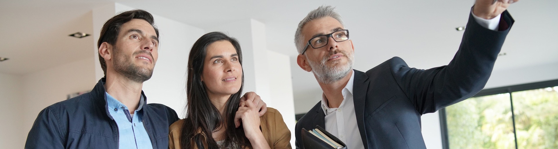 Een man en vrouw bezichtigen een woning samen met een mannelijke makelaar